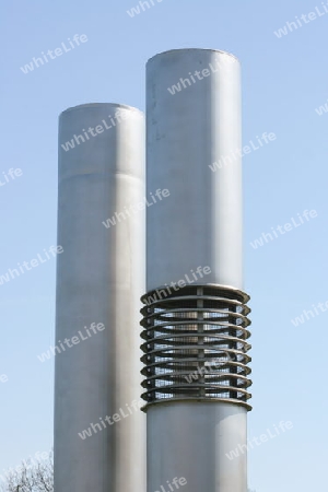 two silver-colored exhaust pipes with blue sky in the background    zwei silberfarbene Abluftrohre mit blauem Himmel im Hintergrundluft-Rohre  Exhaust pipes