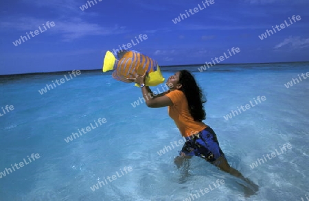 Eine Einheimische Frau an einem Traumstrand auf einer Touristen Insel auf dem Malediven im Indischen Ozean.