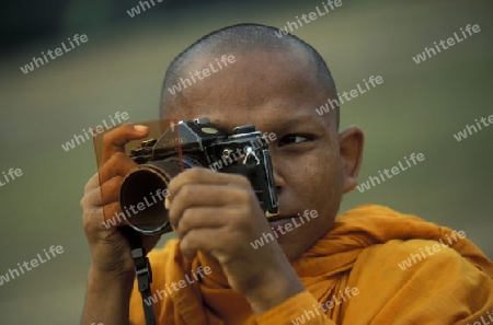 a monk take a pictures at the bayon temple in angkor Thom temples in Angkor at the town of siem riep in cambodia in southeastasia. 