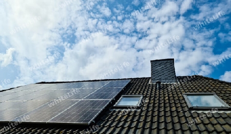 Solar panels producing clean energy on a roof of a residential house with cloud reflections