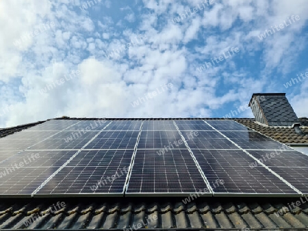 Solar panels producing clean energy on a roof of a residential house with cloud reflections