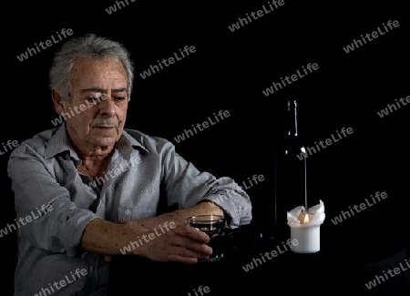 Alter Mann sitzt am Tisch und trinkt Wein
