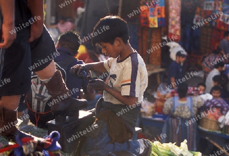 a boy cleans the choes at the Market in the Village of  Chichi or Chichicastenango in Guatemala in central America.   