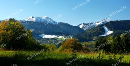 Landschaft mit Schneeberge, Wald und Dorf am See