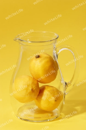 Zitronen in einem Glaskrug auf gelbem Hintergrund