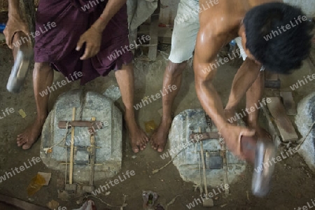 workers pound sheets of Gold leaf at a Gold pounder Factory the City of Mandalay in Myanmar in Southeastasia.