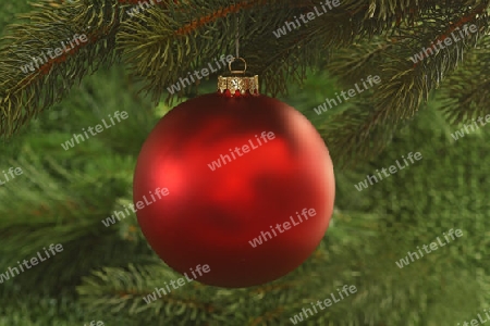 Dekorative Weihnachtskugel an einem Tannenzweig auf gruenem Hintergrund