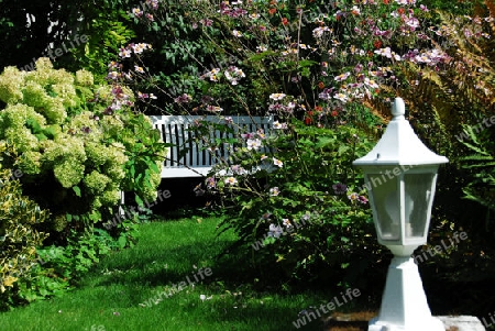 Gartenidylle mit Sitzbank und Laterne