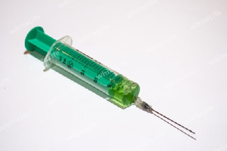 Injektionsspritze mit einem gruenem Medikament und Nadel