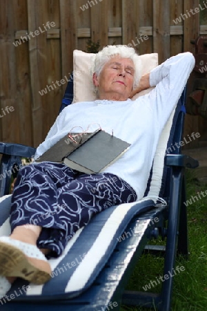Alte Frau liegt im Garten auf Liege und schl?ft