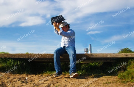 Man on bench raises notebook to the floor - Mann auf Bank wirft Notebook auf den Boden