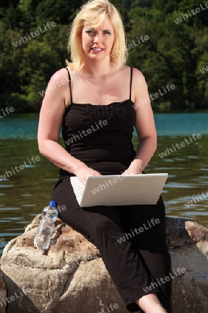 Junge Frau am See mit Laptop 
