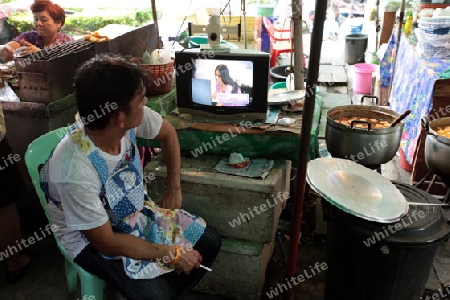 Ein Mann beim Fernseh schauen auf einem Markt in Bangkok der Hauptstadt von Thailand in Suedostasien.  
