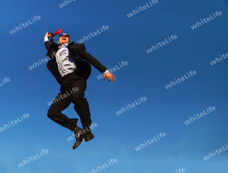 Man in suit with glasses jumping under a blue sky - Mann in Anzug mit Brille und Glatze unter blauem Himmel                               