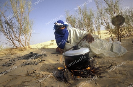 Ein Beduine beim backen von Fladenbrot an Feuerl in der Wueste bei Douz in sueden von Tunesien in Nordafrika.