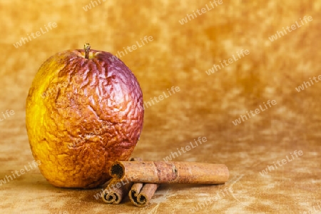 Verschrumpelte Apfel auf rustikalen Hintergrund,mit Zimtstangen
