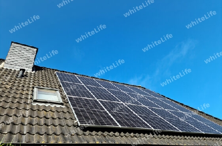 Solar panels producing clean energy on a roof of a residential house with black roof tiles