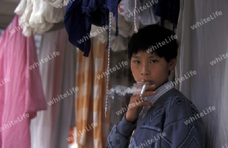 a boy is smoking cigarets at the yangzee river in the three gorges valley up of the three gorges dam project in the province of hubei in china.