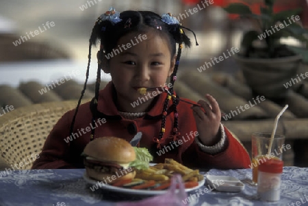 a girl with a hanburger in a restaurant in the town of Yangshou near the city of  Guilin in the Province of Guangxi in china in east asia. 