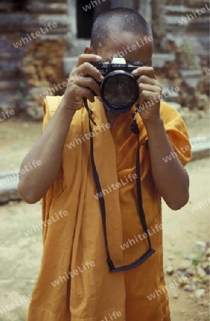 a monk take a pictures at the bayon temple in angkor Thom temples in Angkor at the town of siem riep in cambodia in southeastasia. 