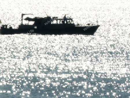 Motorboot als Silhouette auf glitzerndem See