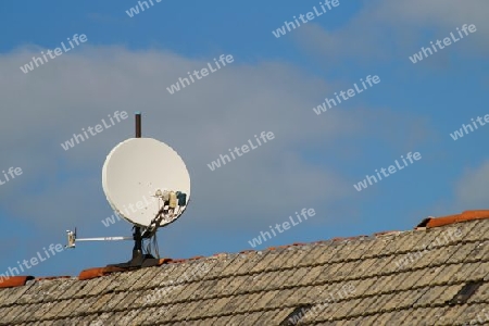 Satellitenantenne an einem Stahlrohr auf einem Dach mit defekten Dachfirst.