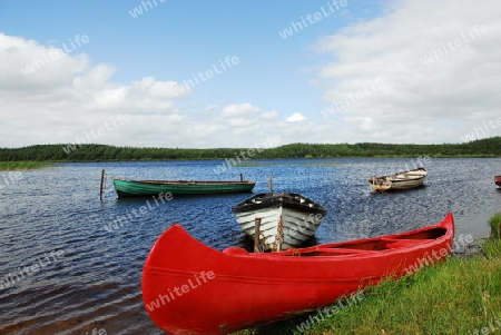 Rotes Kanu und Fischerboote im Hochmoorsee in Irland