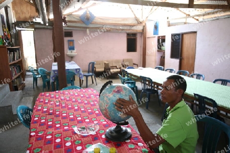 Ein Junger Timori studiert die Welt auf einem Globus in einem Restaurant im Bergdorf Same suedlich von Dili in Ost Timor auf der in zwei getrennten Insel Timor in Asien. 