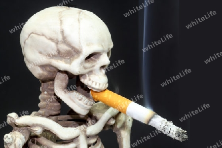 Totenschaedel mit brennender Zigarette auf schwarzen Hintergrund
