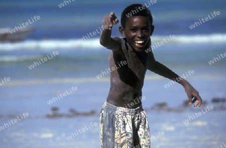 Ein Junge an einem Strand auf der Insel Mahe auf den Seychellen Inseln mit dem Meer des Indische Ozean.