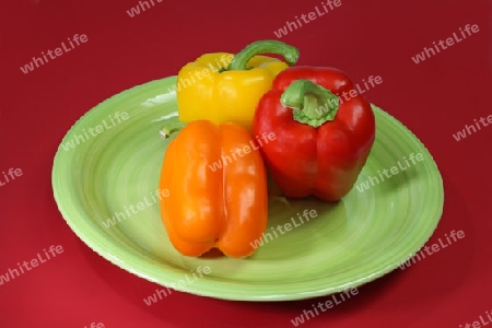 Paprikaschotenmischung auf einem Teller mit rotem Hintergrund