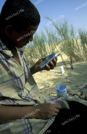 Ein Beduine beim Telefonieren in der Wueste von Douz im Sueden von Tunesien in Nordafrika. 