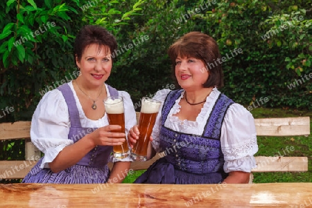 ?ltere bayerische Frauen sitzen im Dirndl zusammen und musizieren bei einer gem?tlichen halbe Wei?bier