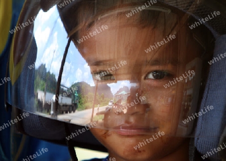 Ein Junge mit Helm auf einem Motorrad auf der Landstrasse 12 beim Dorf Mahaxai Mai von Tham Pa Fa unweit der Stadt Tha Khaek in zentral Laos an der Grenze zu Thailand in Suedostasien.