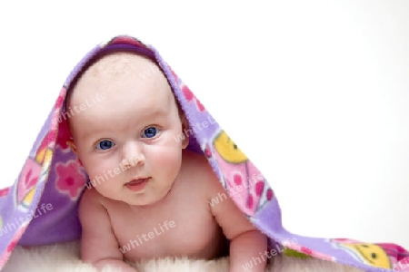 Baby auf Lammfell und bunter Decke