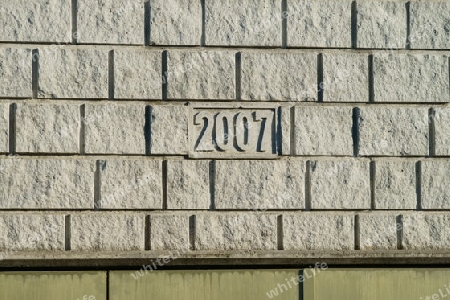 Graue Bruchsteinmauer mit der Erbauungsmarke 2007 in der Mitte.