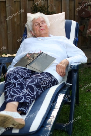 Alte Frau liegt im Garten auf Liege und schl?ft