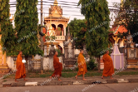Moenche auf ihrem Rundgang am fruehem Morgen vor dem Tempel Wat Sainyaphum in der Stadt Savannahet in zentral Laos an der Grenze zu Thailand in Suedostasien.