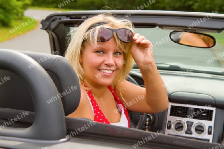 Junge blonde Frau am Steuer eines Cabriolets