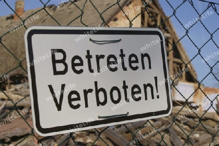 silbernes Schild mit schwarzer Schrift " Betreten Verbote" vor einer Ruine h?ngend