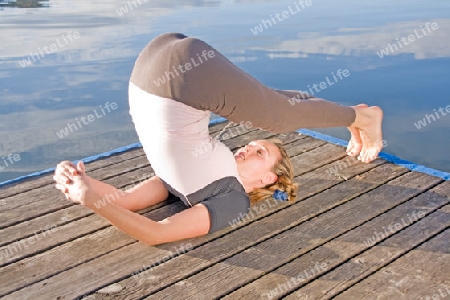 Frau beim Yoga am See 