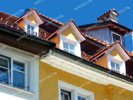 Mittelalterliches Geb?ude mit gelbem Anstrich, roten Dach mit blauem Himmel