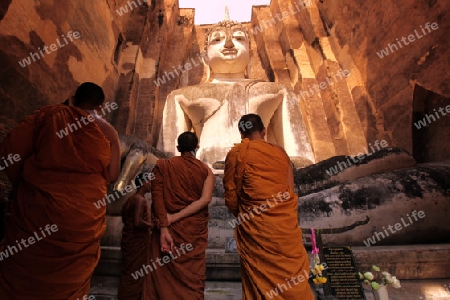 Moenche bestaunen die Buddha Figur  im Wat Si Chum Tempel in der Tempelanlage von Alt-Sukhothai in der Provinz Sukhothai im Norden von Thailand in Suedostasien.
