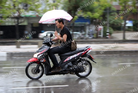 Ein Motorrad auf einer Strasse bei Regenwetter in Chiang Mai in der Provinz Chiang Mai im Norden von Thailand in Suedostasien.