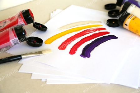 farbige striche,pinsel, und fuenf aufgemachte tuben mit acrylfarben.