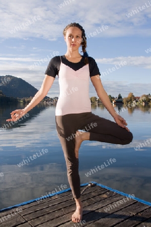 Junge Frau beim Yoga am See
Young woman doing yoga by the lake