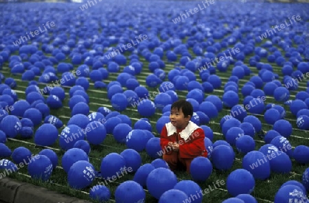 a chila in blue ballons on a economy fair in the city Square of Chengdu in the provinz Sichuan in centrall China.