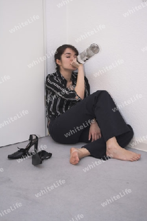 betrunkene Frau sitzt auf dem Fu?boden und trinkt