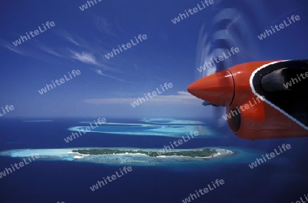 Ein Wasserflugzeug fligt ueber Trauminseln auf den Malediven im Indischen Ozean.