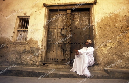 Ein Mann in traditioneller Kleidung in Stone Town der Hauptstadt der Insel Zanzibar oestlich von Tansania im Indischen Ozean.